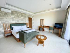 um quarto com uma cama, uma cadeira e uma televisão em Flamingo Bajo Waecicu em Labuan Bajo