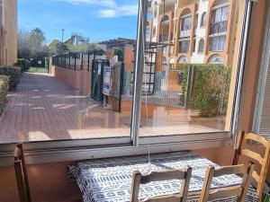 stół i krzesła siedzące przed oknem w obiekcie Studio cabine cosy avec piscine, proche Aqualand et plage, parking disponible, terrasse privative - FR-1-607-159 w Cap d'Agde
