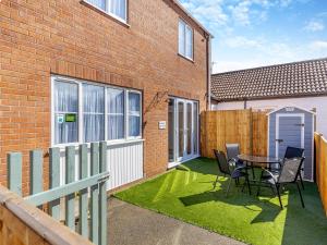 a patio with a table and chairs and a fence at Willows Cottage - Uk42144 in North Somercotes