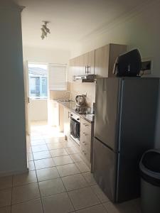 a kitchen with a refrigerator and a tile floor at Dune Crest - 2 Bedroom Apartment in Cape Town