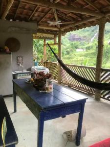 a blue table in a kitchen with a hammock at Refúgio, Aconchego, Aonde nasce o sol e Cachoeira! in Mercês