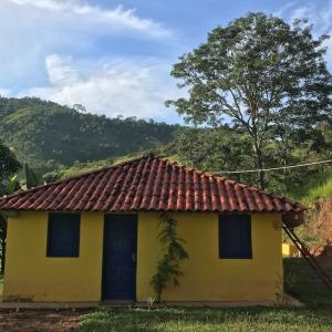 une petite maison jaune avec un toit rouge dans l'établissement Refúgio, Aconchego, Aonde nasce o sol e Cachoeira!, à Mercês