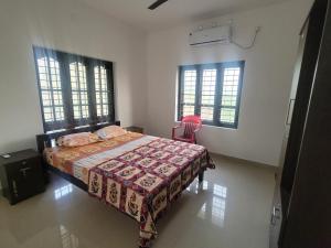 a bedroom with a bed and a chair and windows at Private Room! Alleppey Villa! in Alleppey