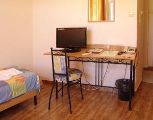 a room with a desk with a television and a bed at Central Family Hotel in Haskovo