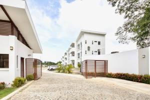 a driveway of a house with white walls and gates at Bright & Airy new Condo, 5 min walk to Jaco Beach! in Jacó