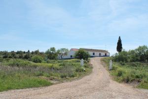 a dirt road in front of a white building at Vale do Boto-Quinta com 3 casas in Castro Marim