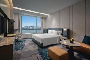 Crowne Plaza Hangzhou Riverside, an IHG Hotel في هانغتشو: غرفة فندقية بسرير ونافذة كبيرة