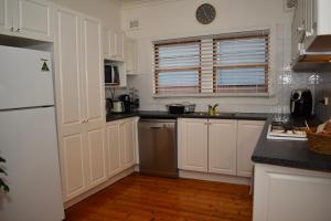a kitchen with white cabinets and a white refrigerator at Wollongong Beach House Living in Gwynneville +10 photos