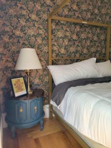 ein Schlafzimmer mit einem Bett und einem Tisch mit einer Lampe in der Unterkunft The Maple Shade Suite in Sussex