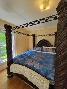 a bedroom with a canopy bed with a blue comforter at The Maple Shade Suite in Sussex