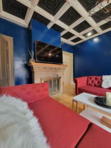 a living room with a red couch and a fireplace at The Maple Shade Suite in Sussex