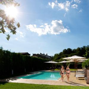 dos mujeres en bikini caminando por una piscina en Locanda Ristorante Gavarini en Bagnone