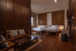 a bedroom with two beds and a couch and a table at neil niwas in Bangkok