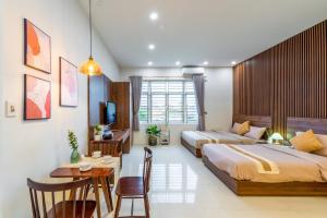1 dormitorio con 2 camas, mesa y escritorio en NM Homestay Danang en Da Nang