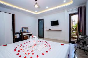 um quarto com uma cama branca com rosas vermelhas em HAI DAO HOI AN VILLA em Hoi An
