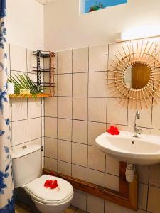 une salle de bain avec toilettes, lavabo et miroir dans l'établissement Pension Mave Mai, à Nuku Hiva