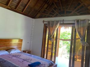 een slaapkamer met een bed en een glazen schuifdeur bij Hotel La Costa International in Puerto López