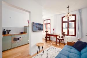 uma sala de estar com um sofá azul e uma cozinha em casanando - LaMaison - neu saniert in ruhiger Innenstadtlage em Leipzig