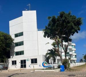 a white building with a sign in front of it at Flat Beira Mar Carapibus in Conde