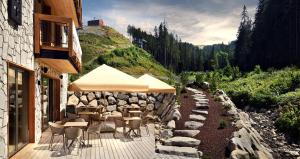 a patio with tables and chairs and a stone wall at Apartmany Demänovka Jasna in Belá +51 photos