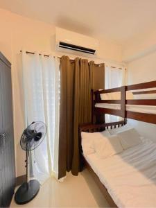 een slaapkamer met een bed en een ventilator naast een raam bij Cozy 1 BR Condo in Fame Residences Mandaluyong City in Manilla