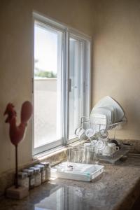 a kitchen counter with glasses and a window at Casa privada con alberca grande in Chetumal