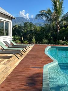 une piscine avec des chaises et une terrasse en bois dans l'établissement Ti Kaz Passion, à Saint-Pierre
