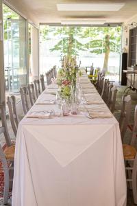 uma mesa longa com toalha de mesa branca e flores sobre ela em La Finestra sul Po - Agriturismo em Monticelli dʼOngina