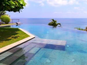 une piscine avec l'océan en arrière-plan dans l'établissement The Luxe Bali - Luxury 4 Bedroom Cliff Ocean Edge Villa Uluwatu, à Uluwatu
