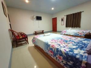 1 dormitorio con 2 camas, TV y silla en Muangchaem House, en Mae Chaem