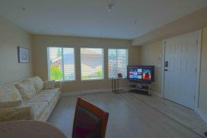 a living room with a couch and a flat screen tv at Cozy Home Nestled in Burke Mountain. in Coquitlam