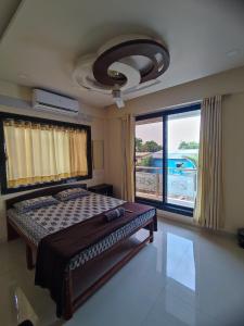 a bedroom with a bed and a large window at Sukhakarta Holiday Home in Veshvi