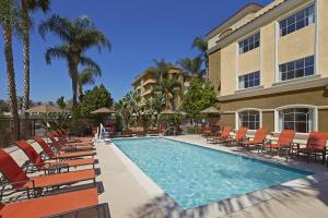 basen z krzesłami i budynek w obiekcie Portofino Inn and Suites Anaheim Hotel w mieście Anaheim