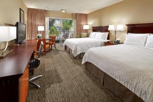 a hotel room with two beds and a flat screen tv at Portofino Inn and Suites Anaheim Hotel in Anaheim