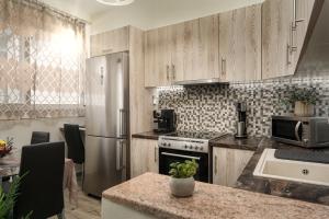 eine Küche mit Holzschränken und einem Edelstahlkühlschrank in der Unterkunft Little Gem in Zakynthos + 21 Fotos