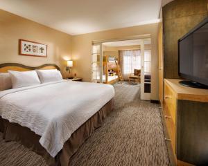 a hotel room with a bed and a flat screen tv at Portofino Inn and Suites Anaheim Hotel in Anaheim