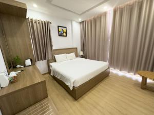Schlafzimmer mit einem Bett, einem Tisch und einem Fenster in der Unterkunft Khách Sạn ĐÔNG DƯƠNG Quy Nhơn in Quy Nhon