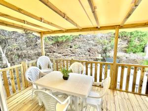 une table et des chaises blanches sur une terrasse en bois dans l'établissement Camping le lac des rêves L'ABRIZEN, à Lattes