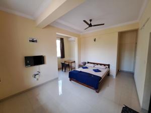 a bedroom with a bed and a flat screen tv at D'souza's Guest House in Tivim