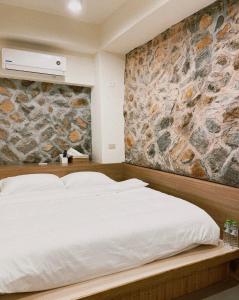 a bedroom with a white bed with a stone wall at 小島上二館 in Chung-liu-ts'un