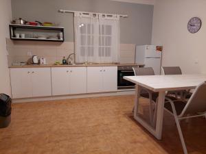 a kitchen with white cabinets and a table with chairs at Amelia's Garden in Kavos