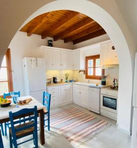 a kitchen with white cabinets and a table with chairs at Plaka Villa 2 Naxos in Plaka