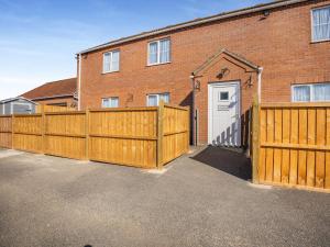 a house with a wooden fence and a garage at Katelans Cottage - Uk42145 in North Somercotes