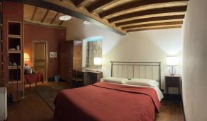 a bedroom with a bed with red sheets and white pillows at Torre Di Ponzano in Barberino di Val dʼElsa