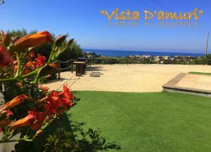 widok na plażę z ławką i kwiatami w obiekcie VISTA D'AMURI w mieście Sciacca