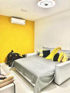 a bedroom with a bed and a yellow wall at Nuevo penthouse con terraza privada, alberca , area infantil y pet friendly in Manzanillo