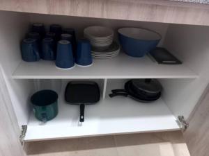 a white shelf with plates and blue cups and bowls at Confortable depto con alberca in Zapopan