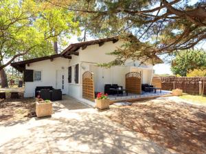 a white house with black furniture and trees at Logis Hôtel Emeraude des Bois in Mimizan-Plage