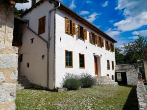 a white building with brown shuttered windows at National monument Mehmedbasica Kuca in Stolac