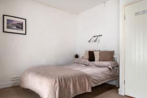 a white bedroom with a bed and a lamp at Miners Cottage in Blaenau-Ffestiniog